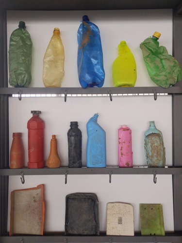 A selection of brightly coloured plastic bottles and trays sit on three shelves.